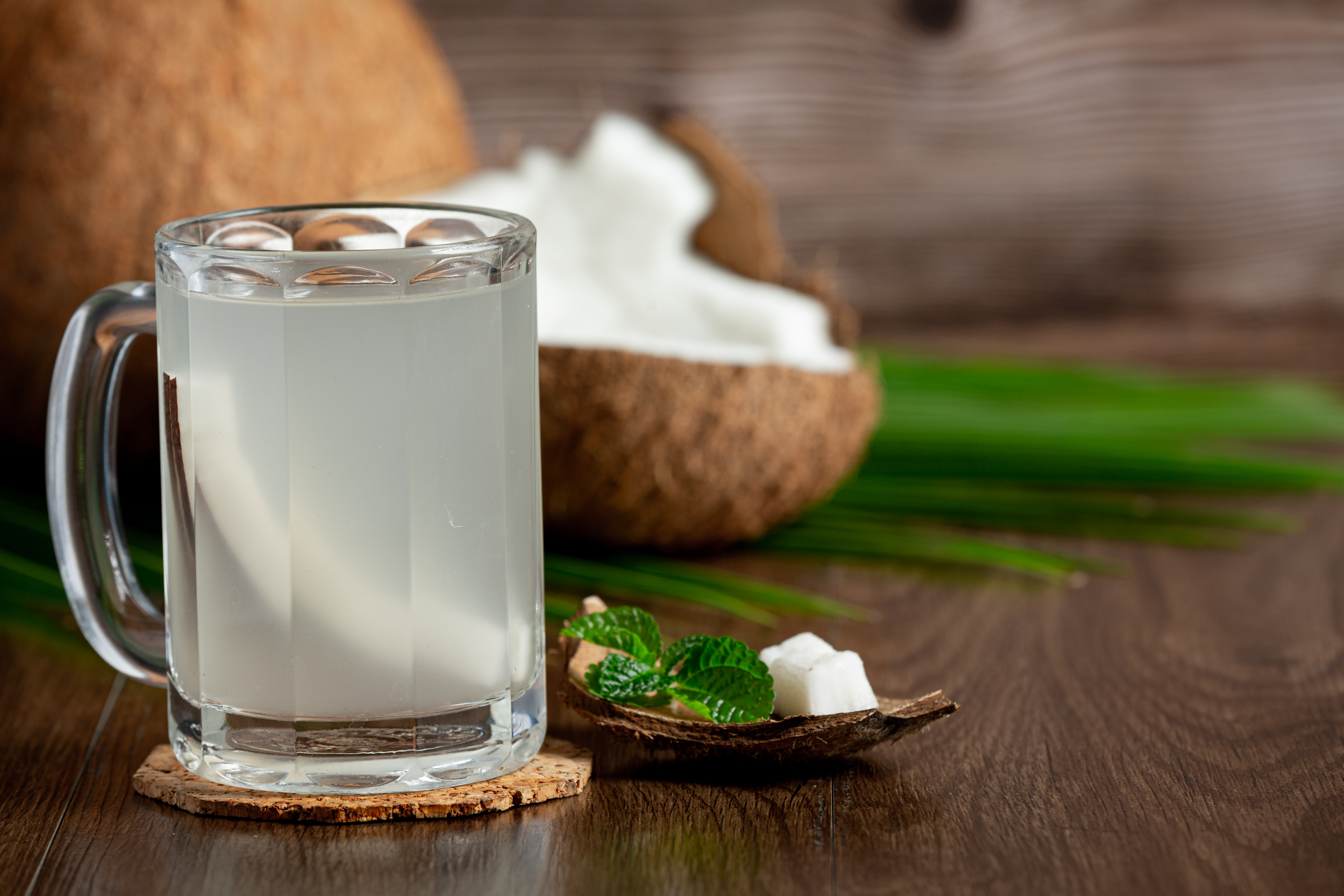a glass of coconut water put on dark wooden background